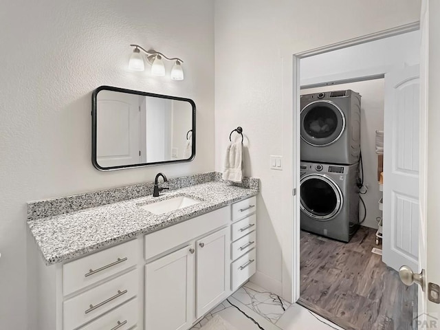 bathroom with baseboards, vanity, and stacked washer / dryer