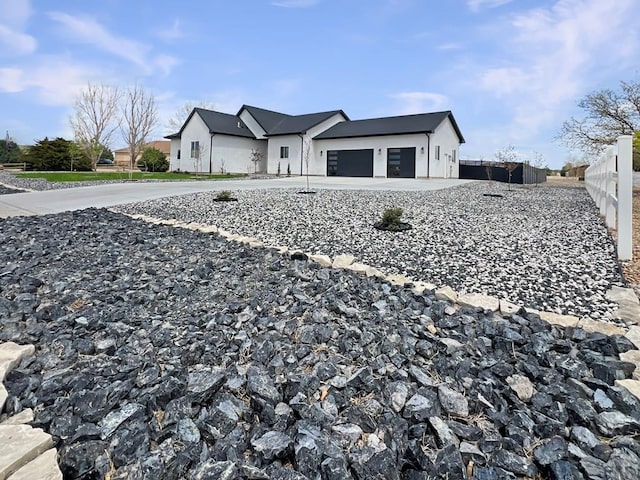 view of front of house with stucco siding, an attached garage, fence, and concrete driveway