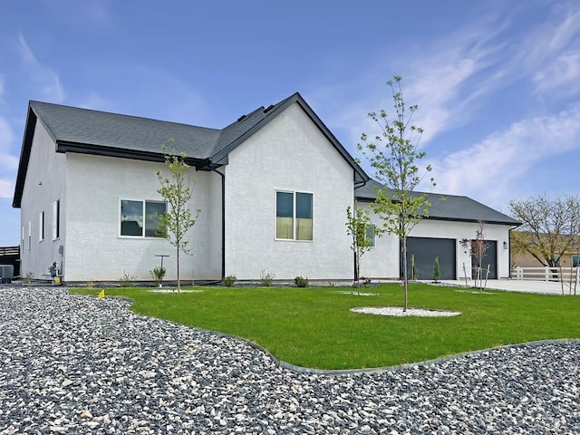 back of house featuring stucco siding, central AC unit, a yard, and a garage