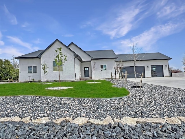 modern inspired farmhouse with stucco siding, an attached garage, driveway, and a front yard