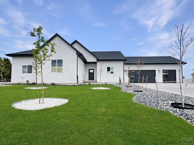 rear view of property with stucco siding, a yard, an attached garage, and concrete driveway