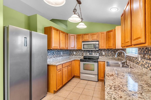kitchen with hanging light fixtures, a sink, vaulted ceiling, stainless steel appliances, and light tile patterned flooring
