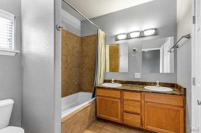 bathroom featuring a sink, tiled shower / bath combo, toilet, and tile patterned flooring