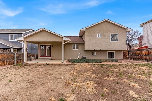 rear view of house with a patio area, stucco siding, and a fenced backyard
