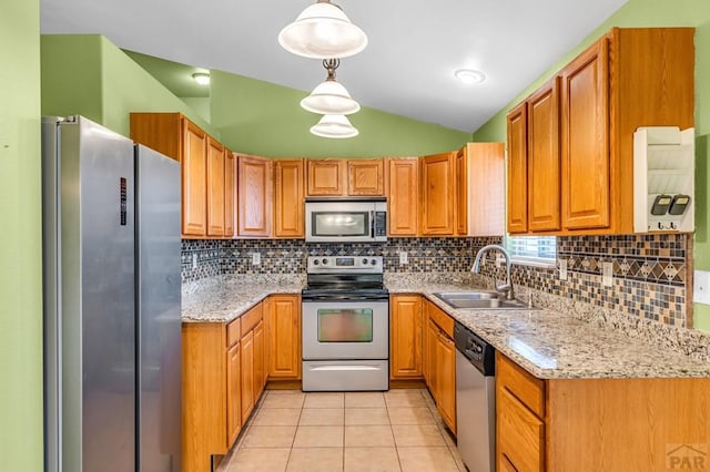 kitchen with light tile patterned floors, light stone countertops, vaulted ceiling, a sink, and stainless steel appliances