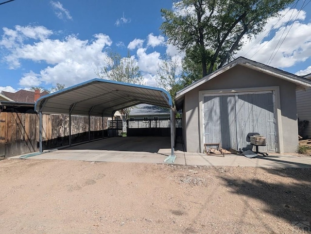 view of vehicle parking with a carport, dirt driveway, and fence