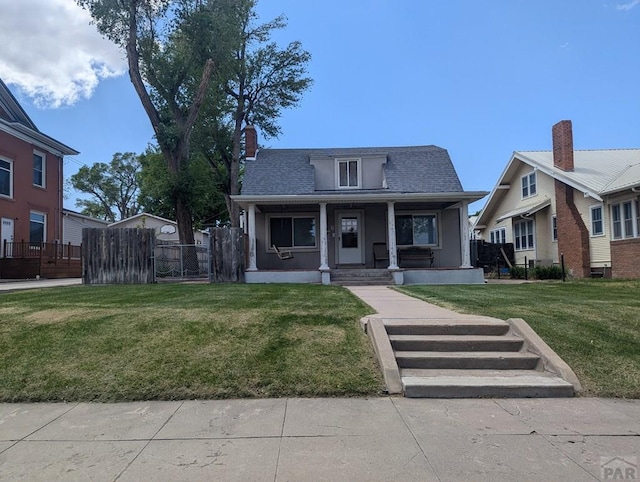 bungalow with fence, covered porch, a front yard, and a shingled roof