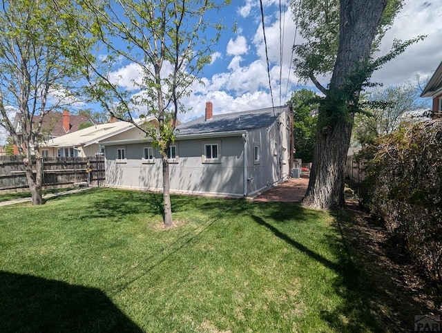rear view of property with a chimney, fence private yard, and a yard