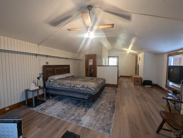 bedroom featuring multiple windows, wood finished floors, vaulted ceiling, and baseboards