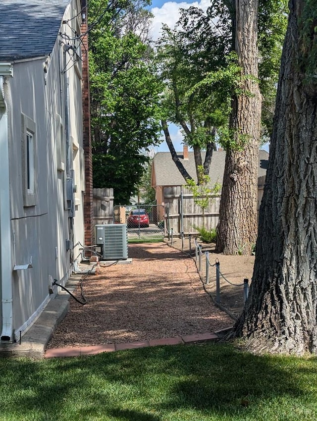 view of yard with central air condition unit and fence