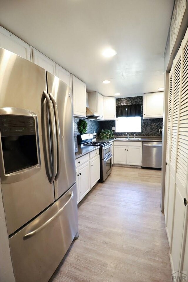 kitchen with tasteful backsplash, appliances with stainless steel finishes, dark countertops, and white cabinets