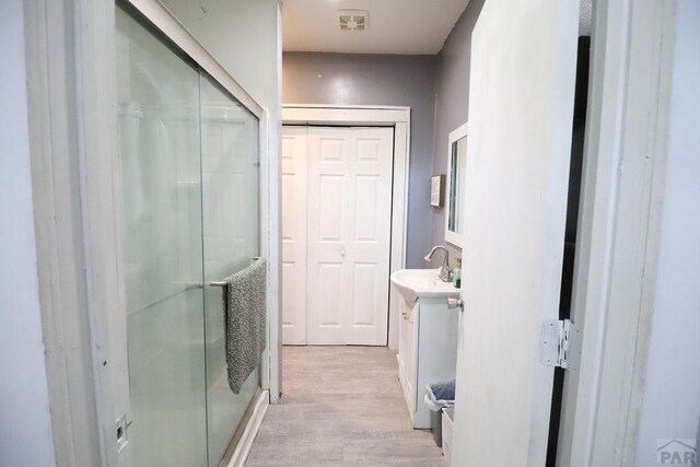 full bath with a stall shower, visible vents, wood finished floors, and vanity