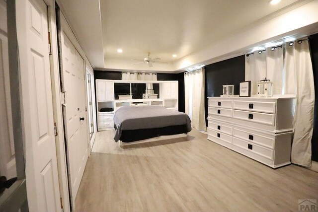 bedroom with a tray ceiling, light wood-style flooring, and recessed lighting