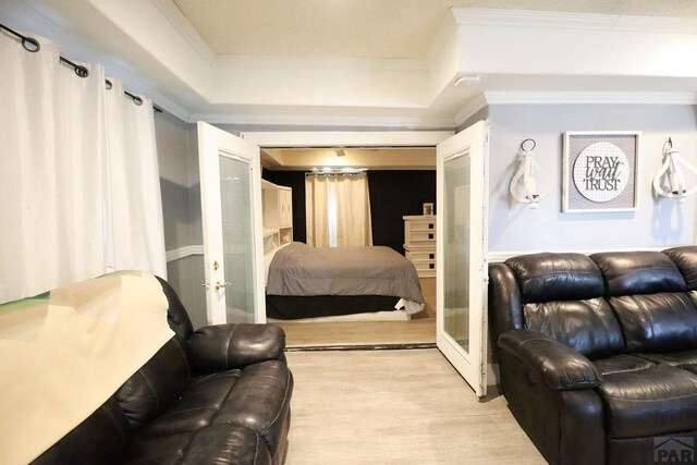 bedroom with light wood-style floors, crown molding, and french doors