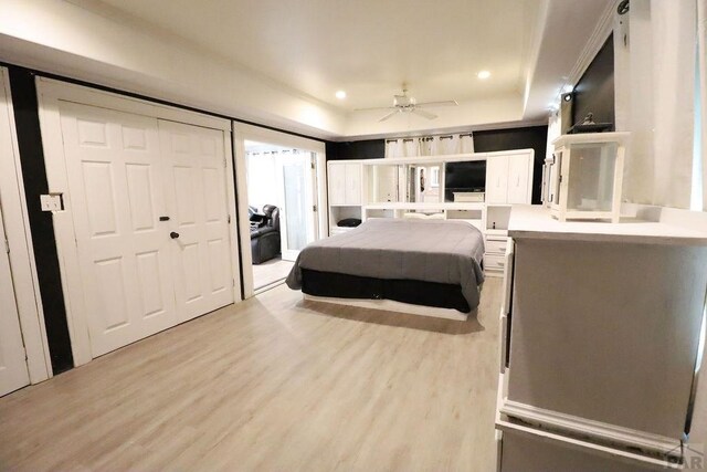 bedroom with light wood finished floors, a raised ceiling, and recessed lighting