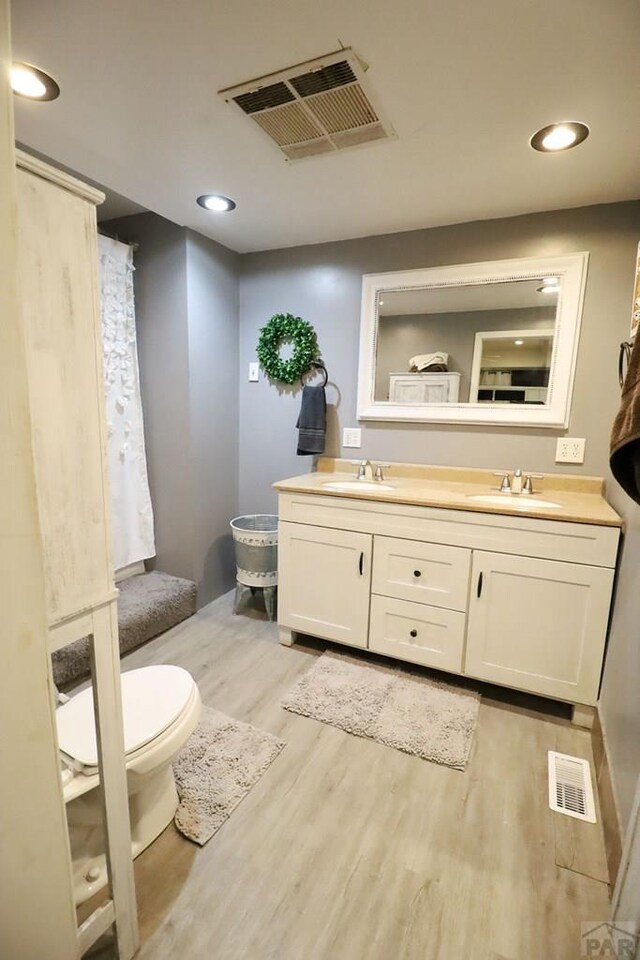 bathroom featuring visible vents, a sink, and wood finished floors