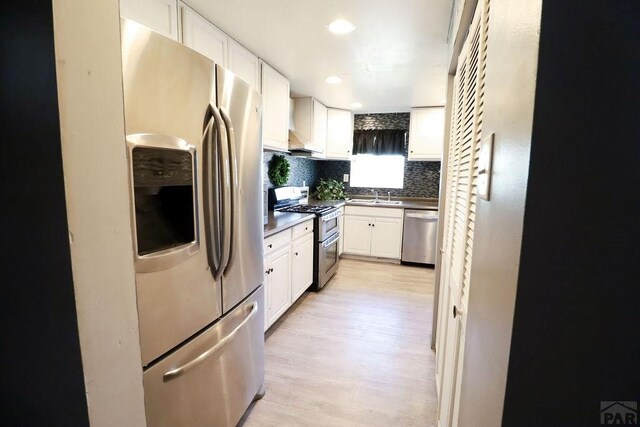 kitchen featuring appliances with stainless steel finishes, dark countertops, white cabinetry, and a sink