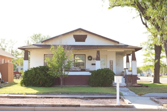 view of front of house featuring brick siding, a front lawn, and a porch