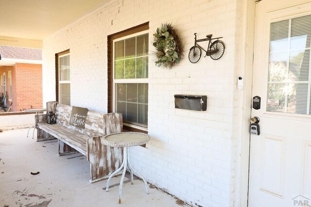 entrance to property featuring covered porch and brick siding