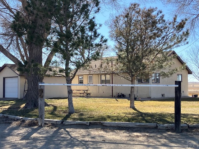 single story home featuring a garage, a front yard, and stucco siding