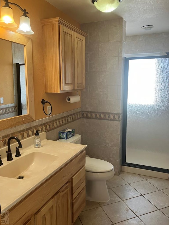 full bathroom with tile patterned flooring, toilet, vanity, tile walls, and a shower stall