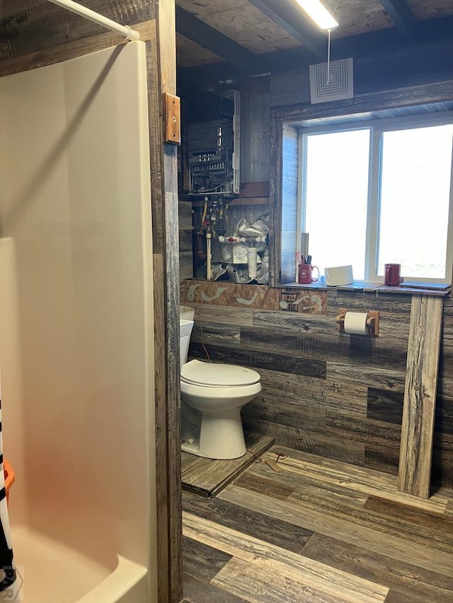 bathroom with a shower, tile walls, toilet, and wood finished floors