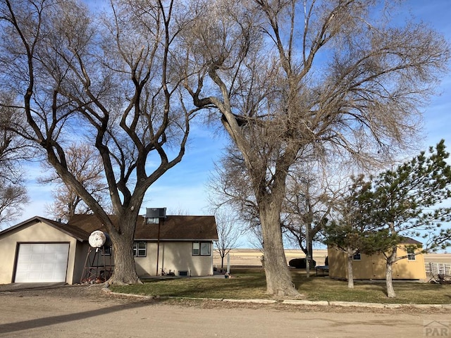 view of front of property featuring a front lawn, driveway, stucco siding, and a garage