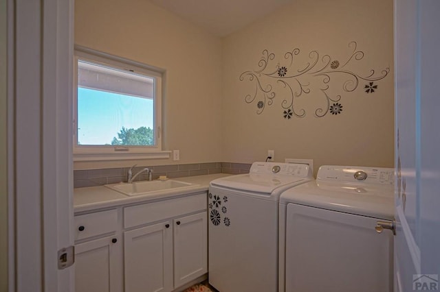 laundry area with cabinet space, washing machine and dryer, and a sink