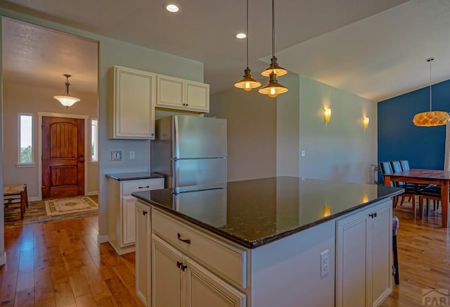 kitchen with a center island, hanging light fixtures, light wood-style floors, freestanding refrigerator, and white cabinetry