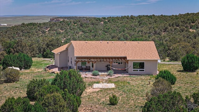 exterior space featuring a forest view, a patio area, and stucco siding