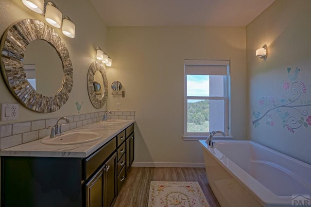 bathroom featuring double vanity, wood finished floors, a sink, and baseboards