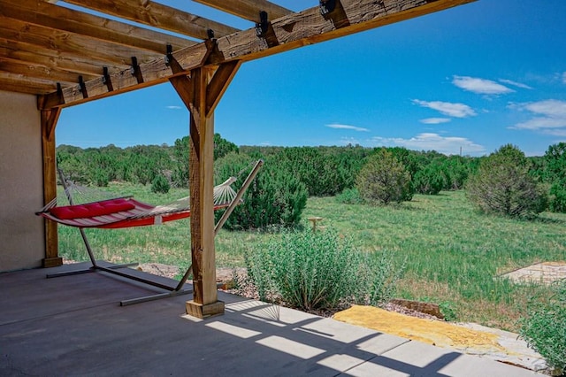 view of patio / terrace featuring a wooded view and a pergola
