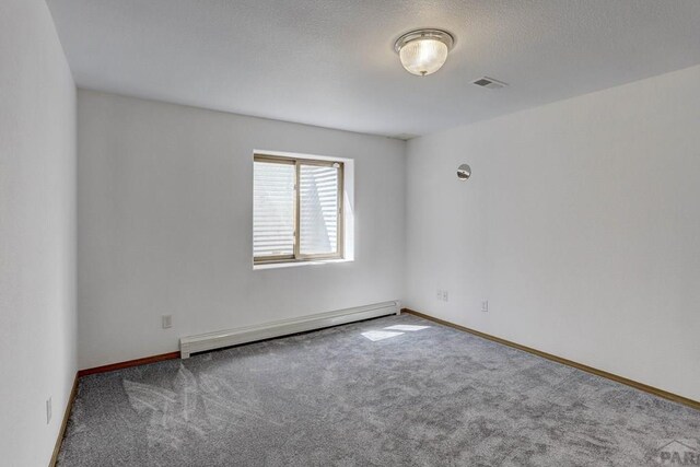 unfurnished room with baseboard heating, carpet flooring, visible vents, and baseboards