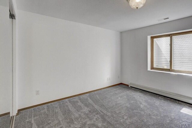 empty room with carpet, visible vents, baseboard heating, and baseboards