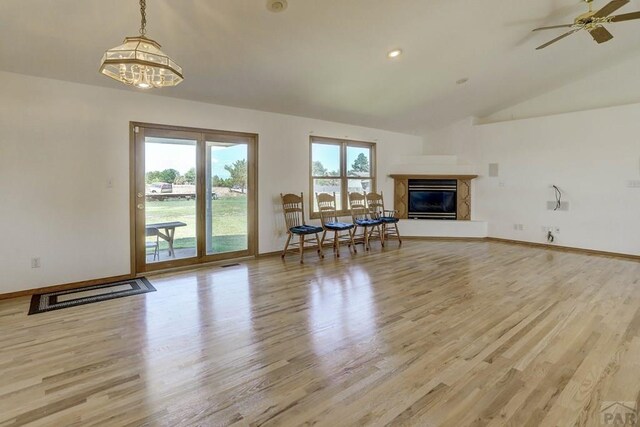 unfurnished living room with lofted ceiling, light wood finished floors, baseboards, and a high end fireplace