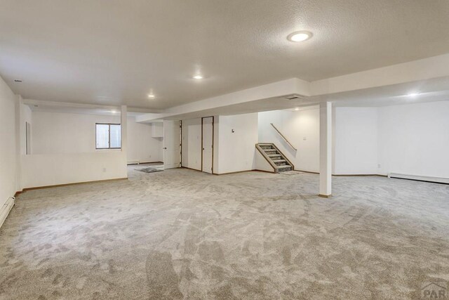 basement with light carpet, a baseboard radiator, stairway, and baseboards