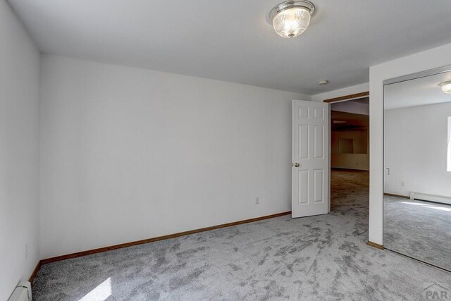 unfurnished bedroom featuring baseboards, a baseboard radiator, and light colored carpet