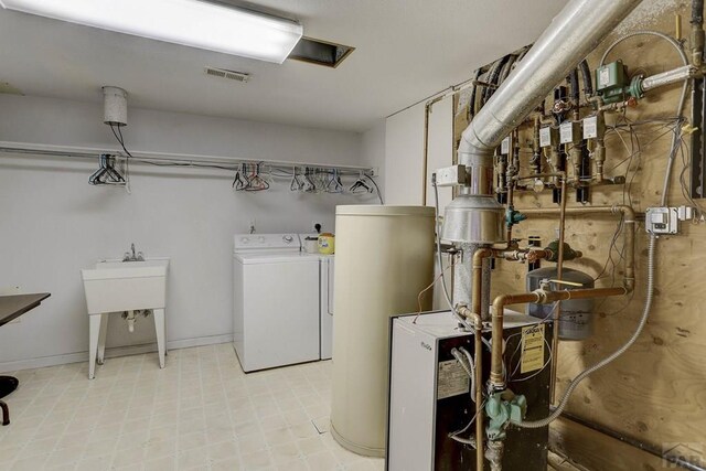 laundry area with electric water heater, laundry area, visible vents, washer and dryer, and a heating unit