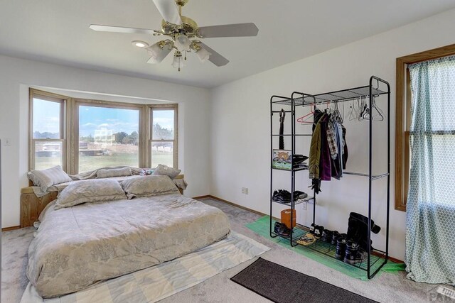 carpeted bedroom with ceiling fan and baseboards