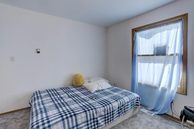 bedroom with baseboards, visible vents, and light colored carpet