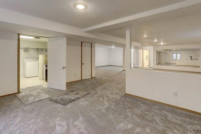 finished basement featuring light colored carpet, washer and clothes dryer, and baseboards