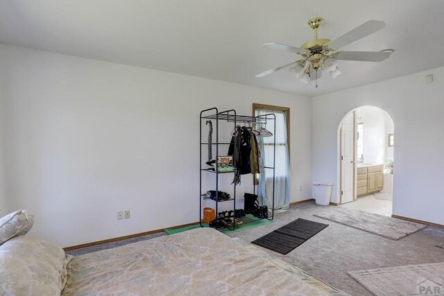 interior space with arched walkways, light carpet, ceiling fan, and baseboards