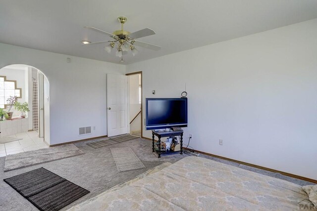 living room with arched walkways, ceiling fan, light tile patterned flooring, visible vents, and baseboards