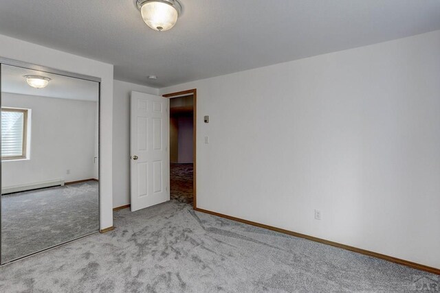 unfurnished bedroom with light carpet, baseboard heating, and baseboards