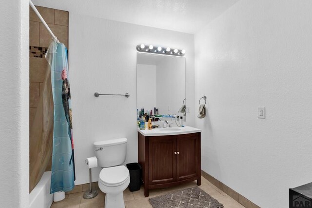 bathroom featuring toilet, shower / bath combo with shower curtain, vanity, baseboards, and tile patterned floors