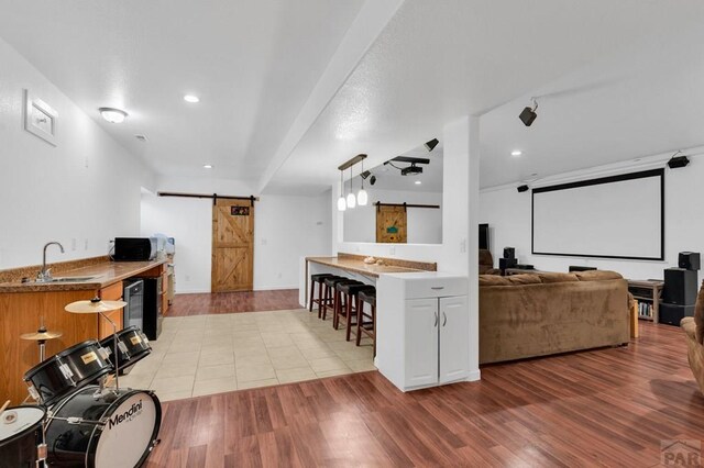 kitchen with a sink, a barn door, a kitchen bar, and light wood-style flooring