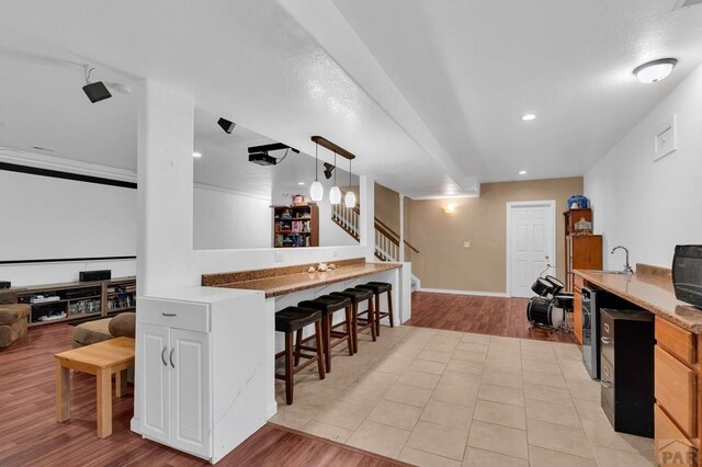 kitchen featuring a peninsula, a breakfast bar, a sink, hanging light fixtures, and light wood-type flooring