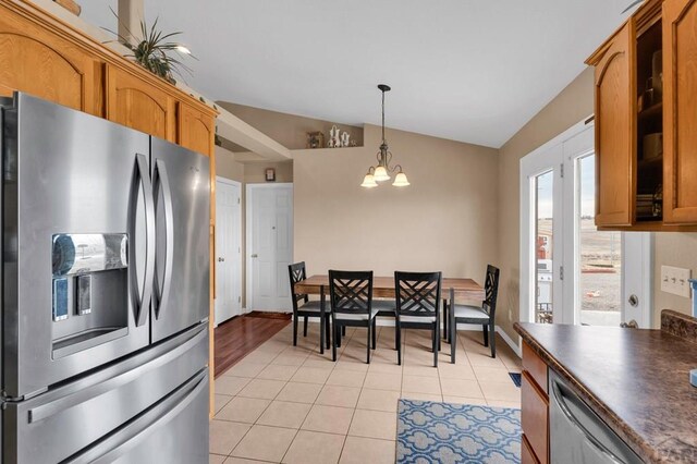 kitchen with decorative light fixtures, stainless steel appliances, brown cabinetry, dark countertops, and glass insert cabinets