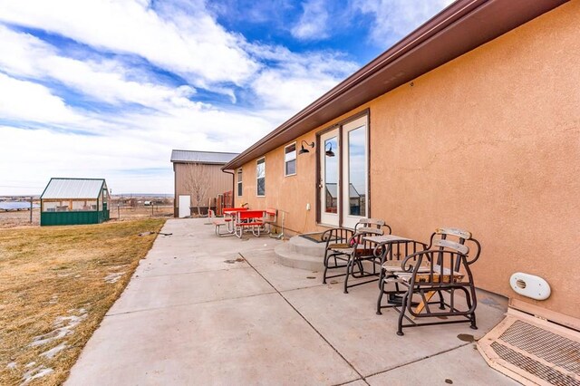 view of patio with a greenhouse, outdoor dining area, and an outdoor structure