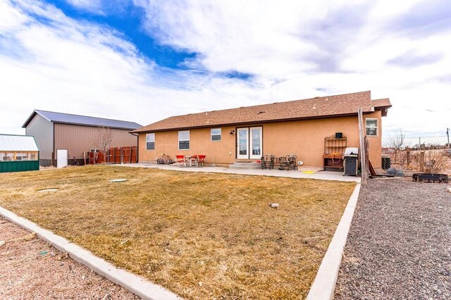 rear view of house featuring a yard, a patio area, fence, and stucco siding